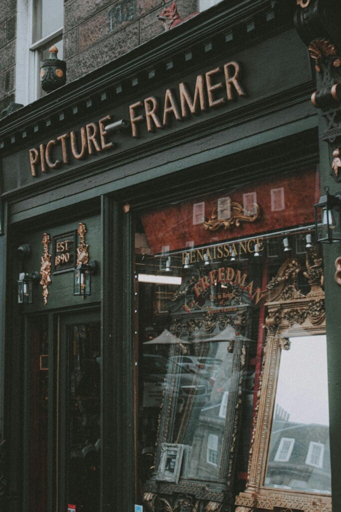 A vintage looking storefront that boasts Picture-Framer, and has frames in the window with the word "renaissance"
