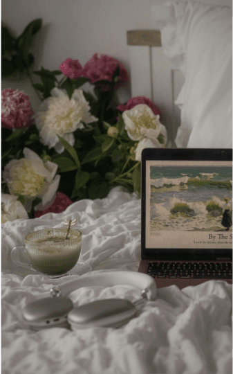 Computer on a bed with flowers in the background opened to a website